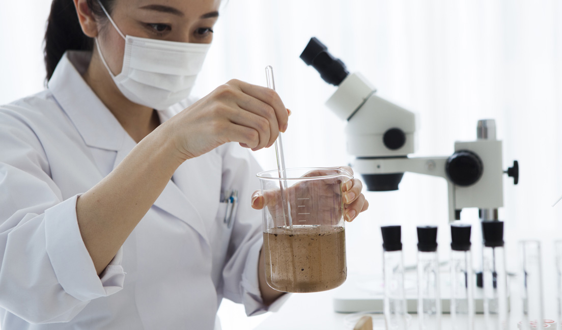 A woman in a lab stirring a liquid in a beaker